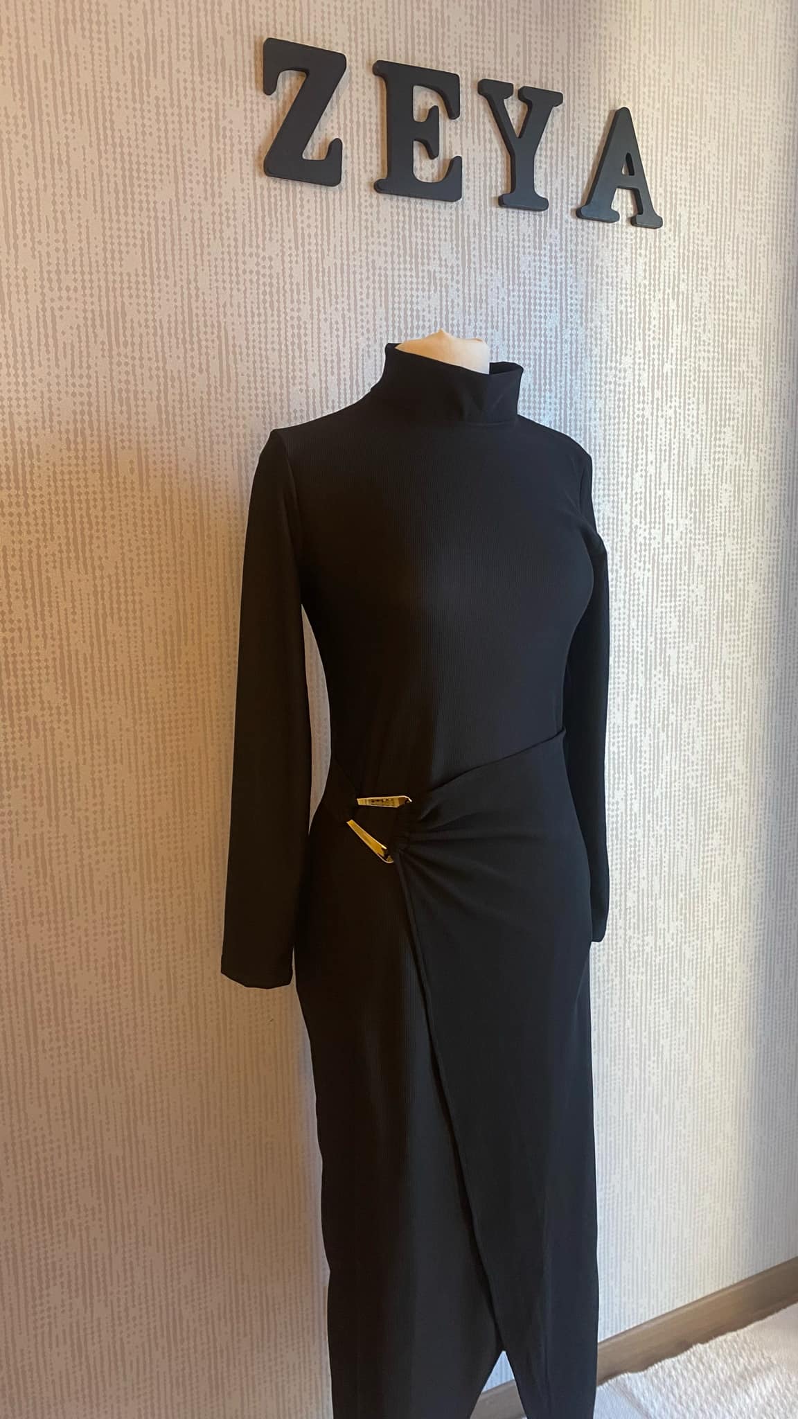 "Robe Aicha noire sophistiquée, texture brillante, fente latérale audacieuse et boucle dorée unique. Parfaite pour les soirées et événements élégants."