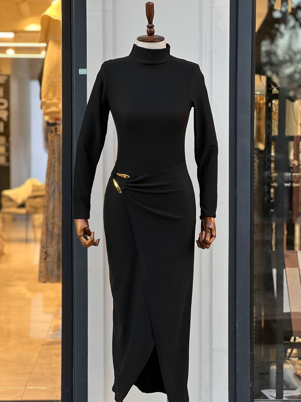 "Robe Aicha noire sophistiquée, texture brillante, fente latérale audacieuse et boucle dorée unique. Parfaite pour les soirées et événements élégants."